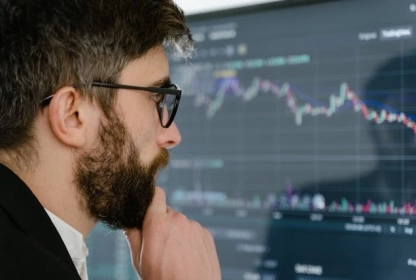 Trader sitting in an office in front of a computer with trading charts on the screen, close look.