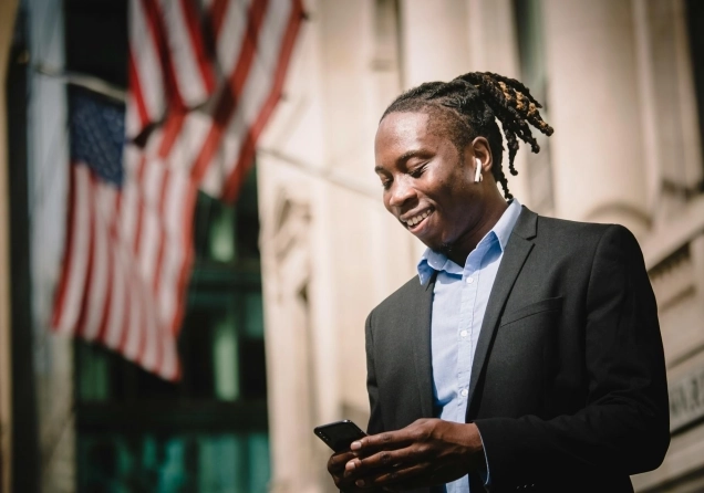 Young Black trader on Wall Street looking at his phone.