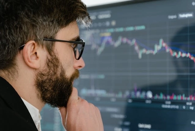 Trader sitting in an office in front of a computer with trading charts on the screen, close look.